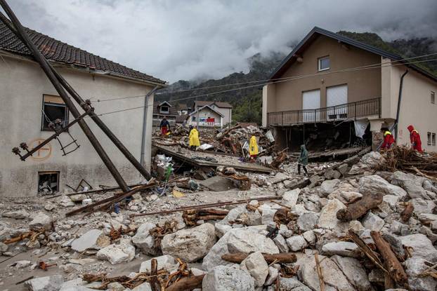 Rescue workers walk among debris following a landslide in the flooded village of Donja Jablanica