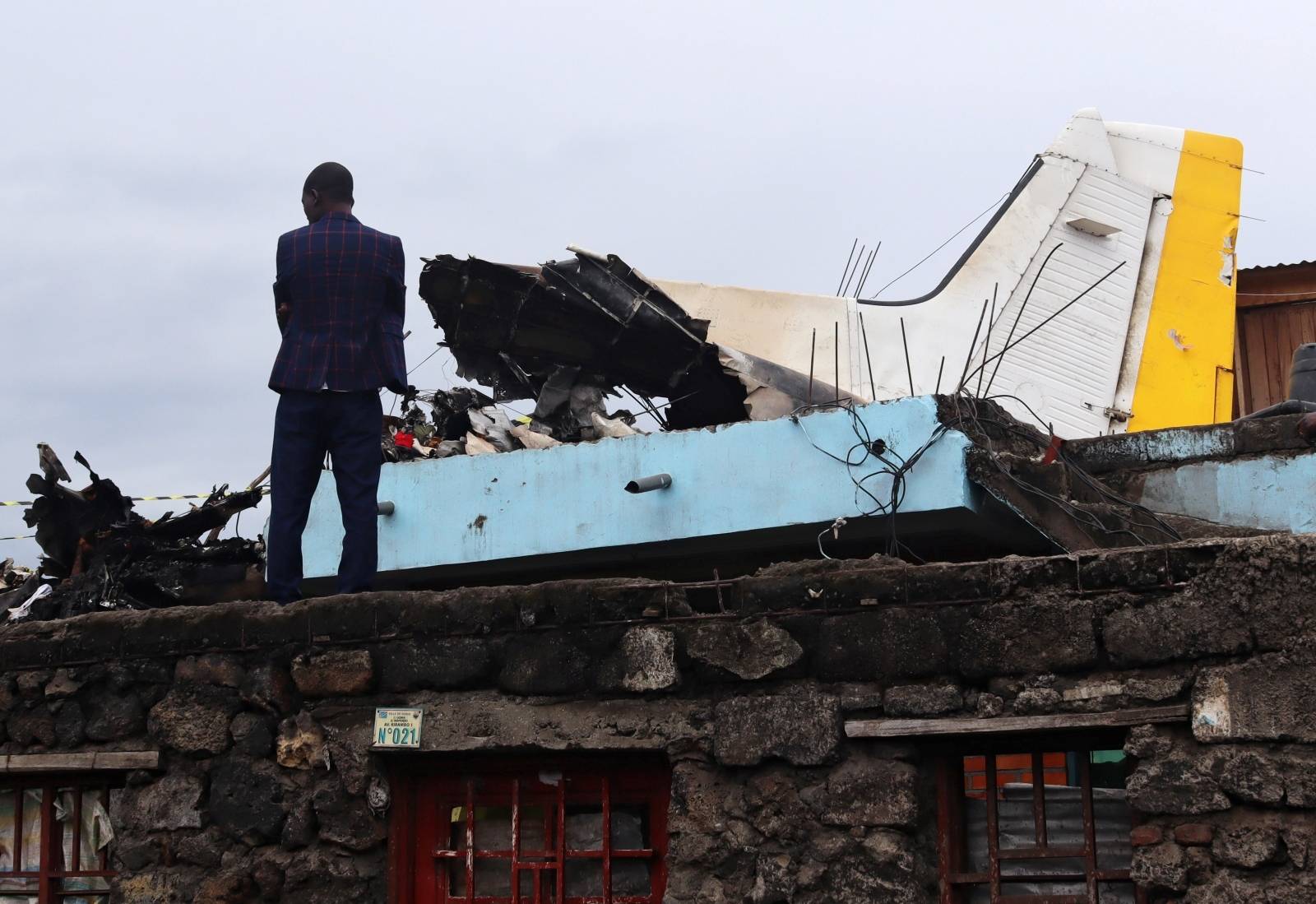 A man stands at the site where a plane Dornier 228-200 plane operated by local company Busy Bee crashed into a densely populated neighborhood in Goma