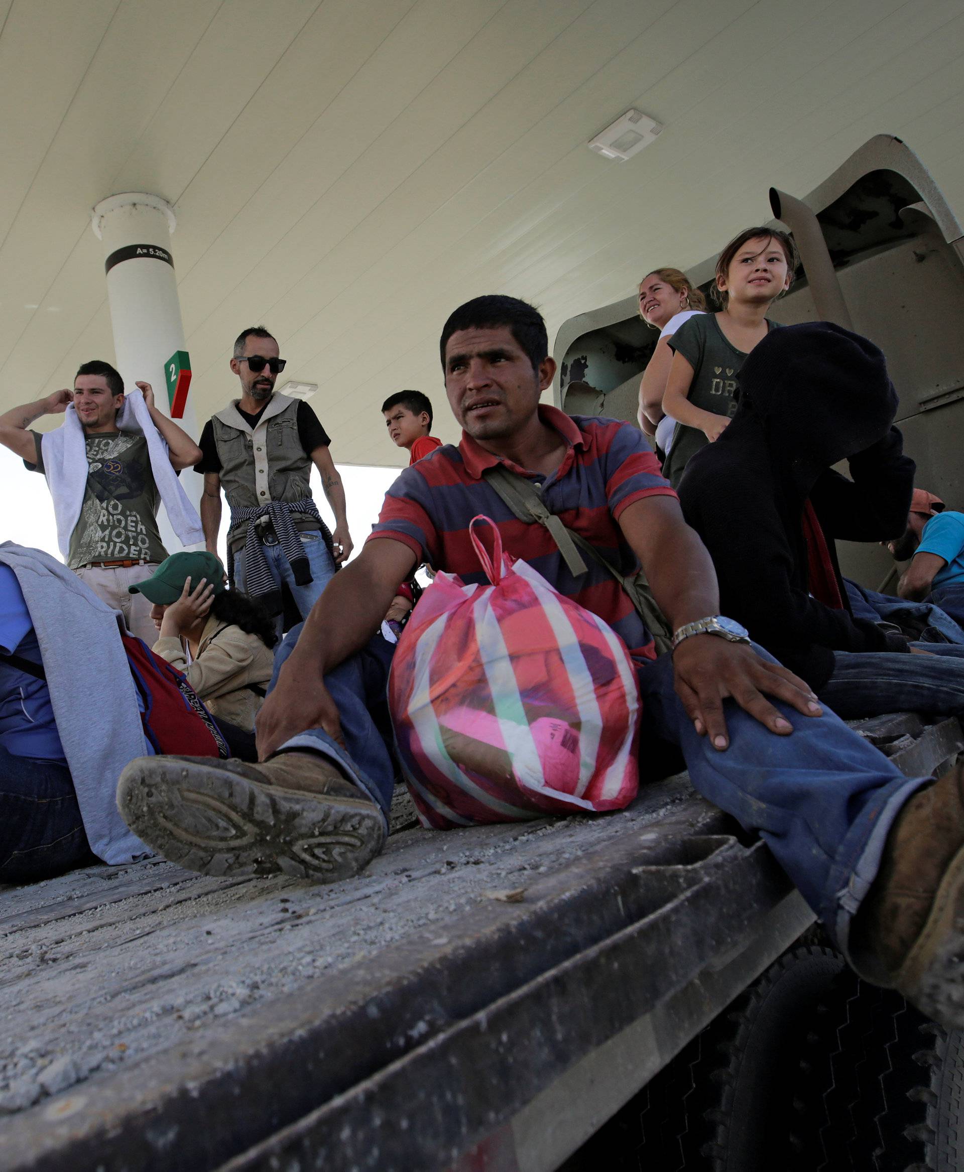 Hondurans, part of a new caravan of migrants travelling towards the United States, sit on a trailer as they hitch a ride in Cucuyagua