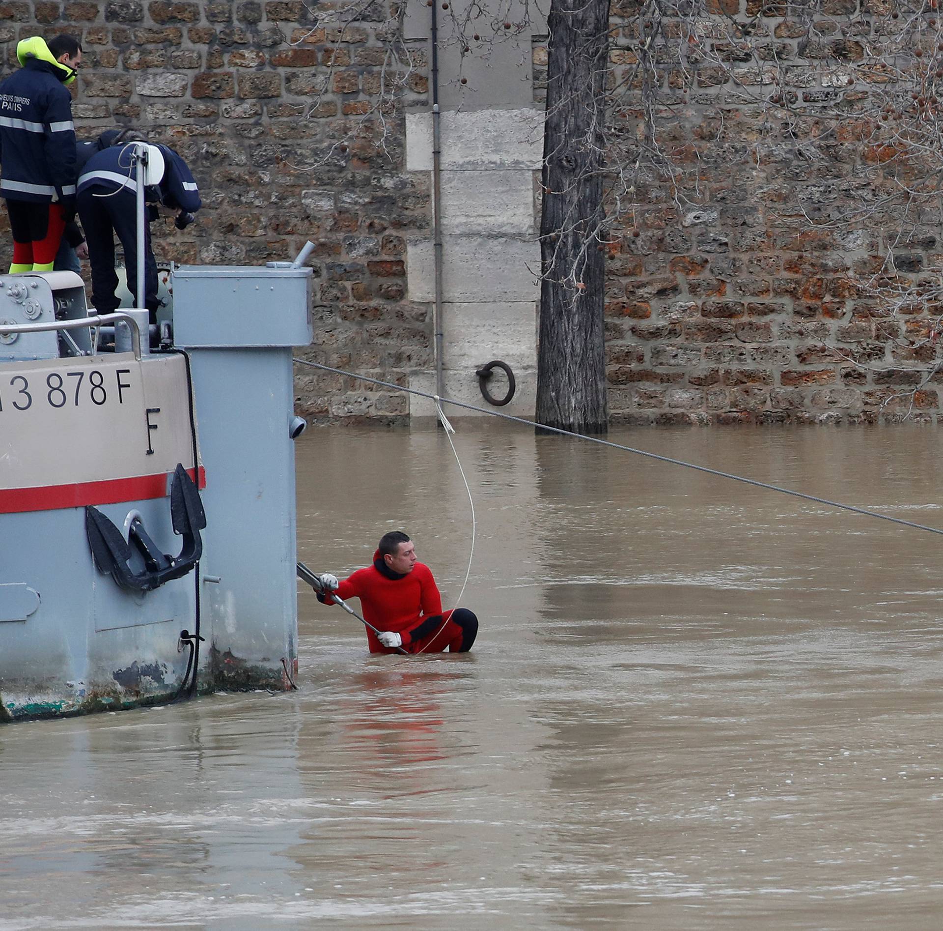 A Paris fire-brigade diver checks the mooring-ropes of a peniche boat moored on the flooded banks of the Seine River in Paris