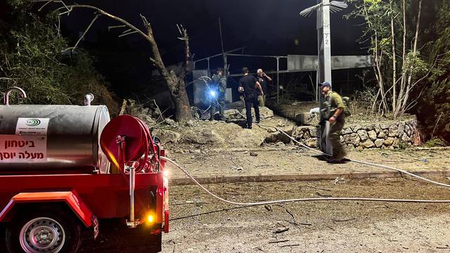 Israeli soldiers and other officials work at the site where a rocket landed after it was fired from Lebanon, amid cross-border hostilities between Hezbollah and Israeli forces, in Tzuriel