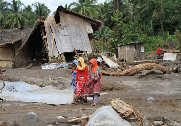 Residents walk in a village devastated by flashfloods in Salvador, Lanao del Norte