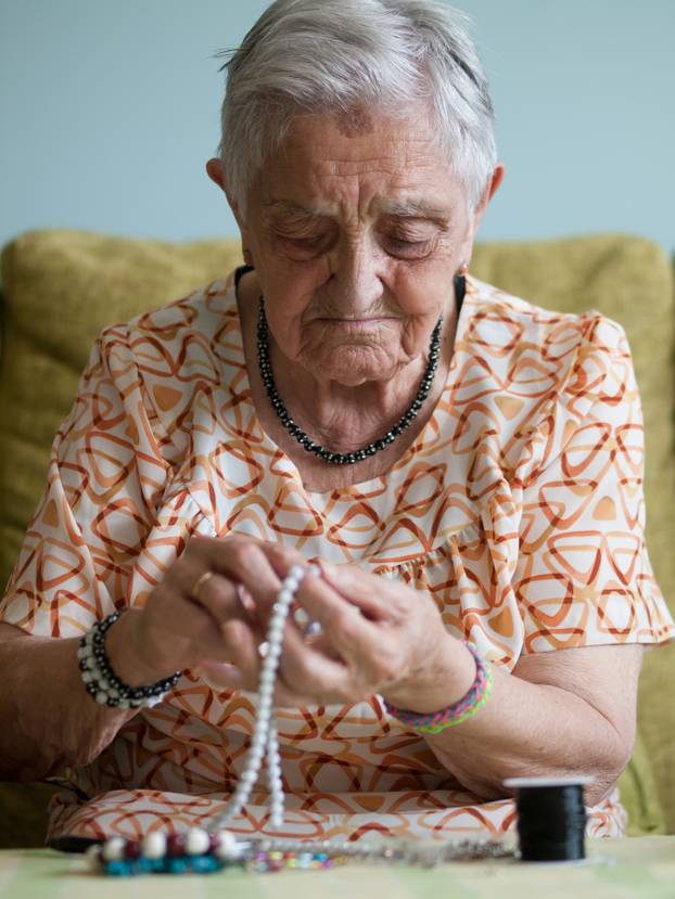 Elderly woman making necklaces 
