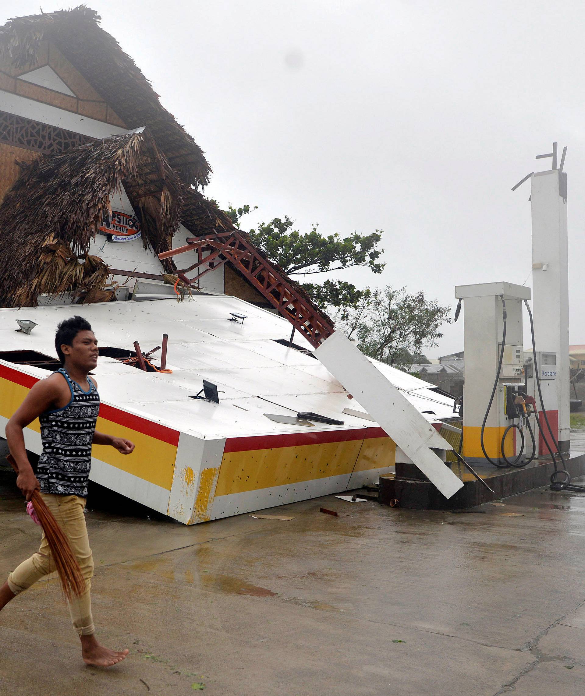 A resident runs past a collapsed roof of a petrol station after Typhoon Haima struck San Nicolas, Ilocos Norte