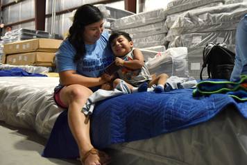 Lopez plays with her son in the warehouse at Gallery Furniture in Houston