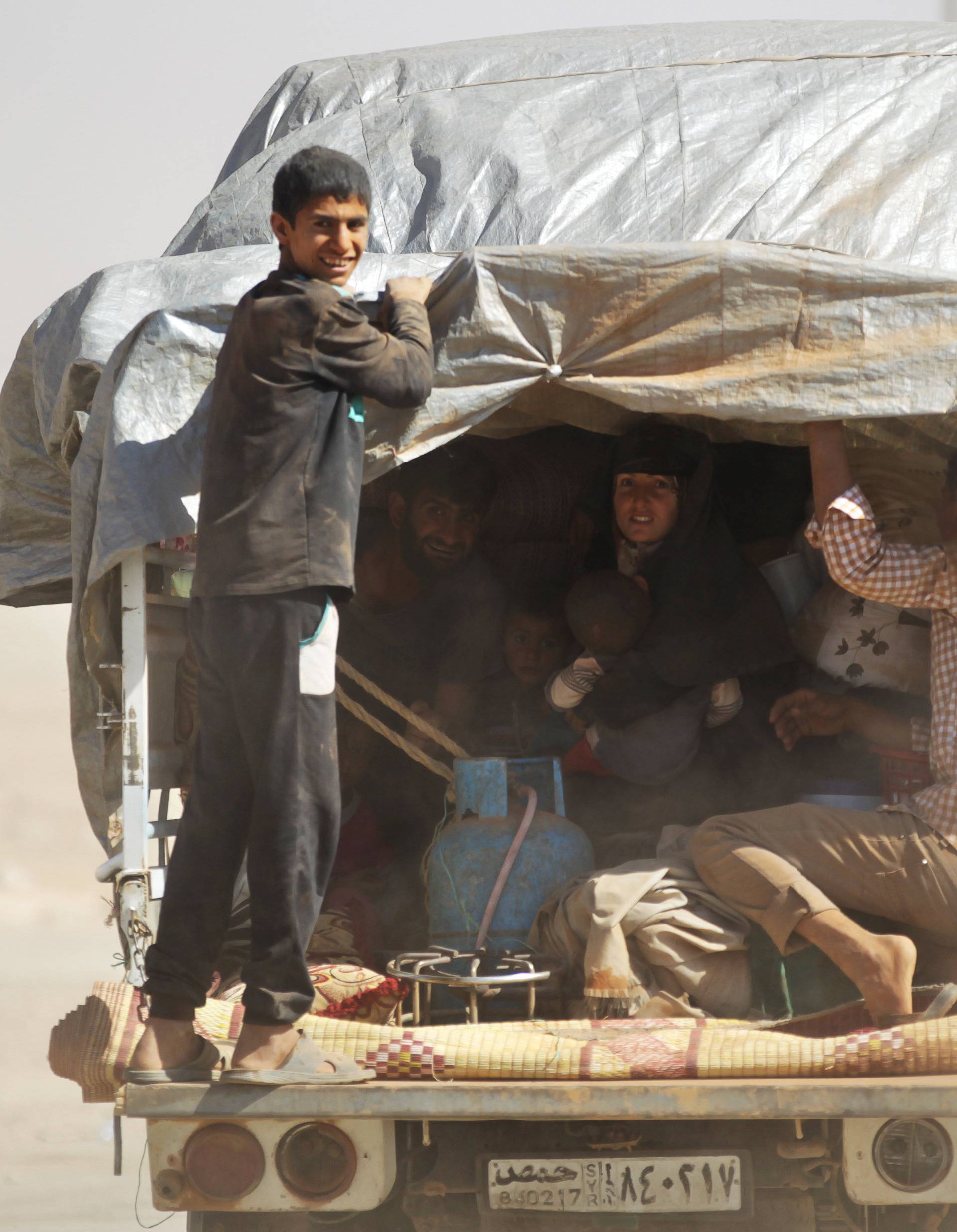 People, who fled from Islamic State-controlled areas, ride a pick-up truck upon their arrival in Turkman Bareh village, after rebel fighters advanced in the area, in northern Aleppo Governorate