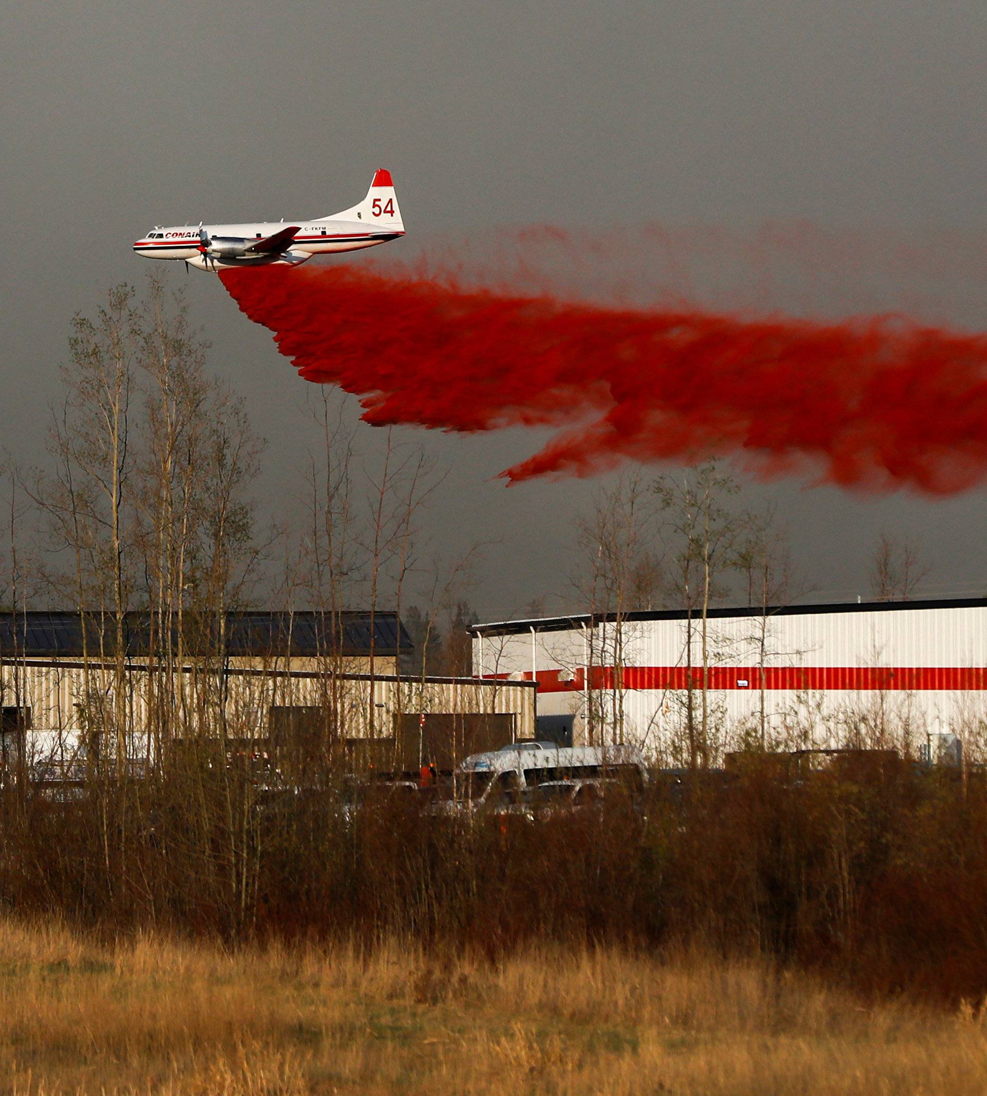 A plane flies low to dump fire retardant on wildfires near Fort McMurray