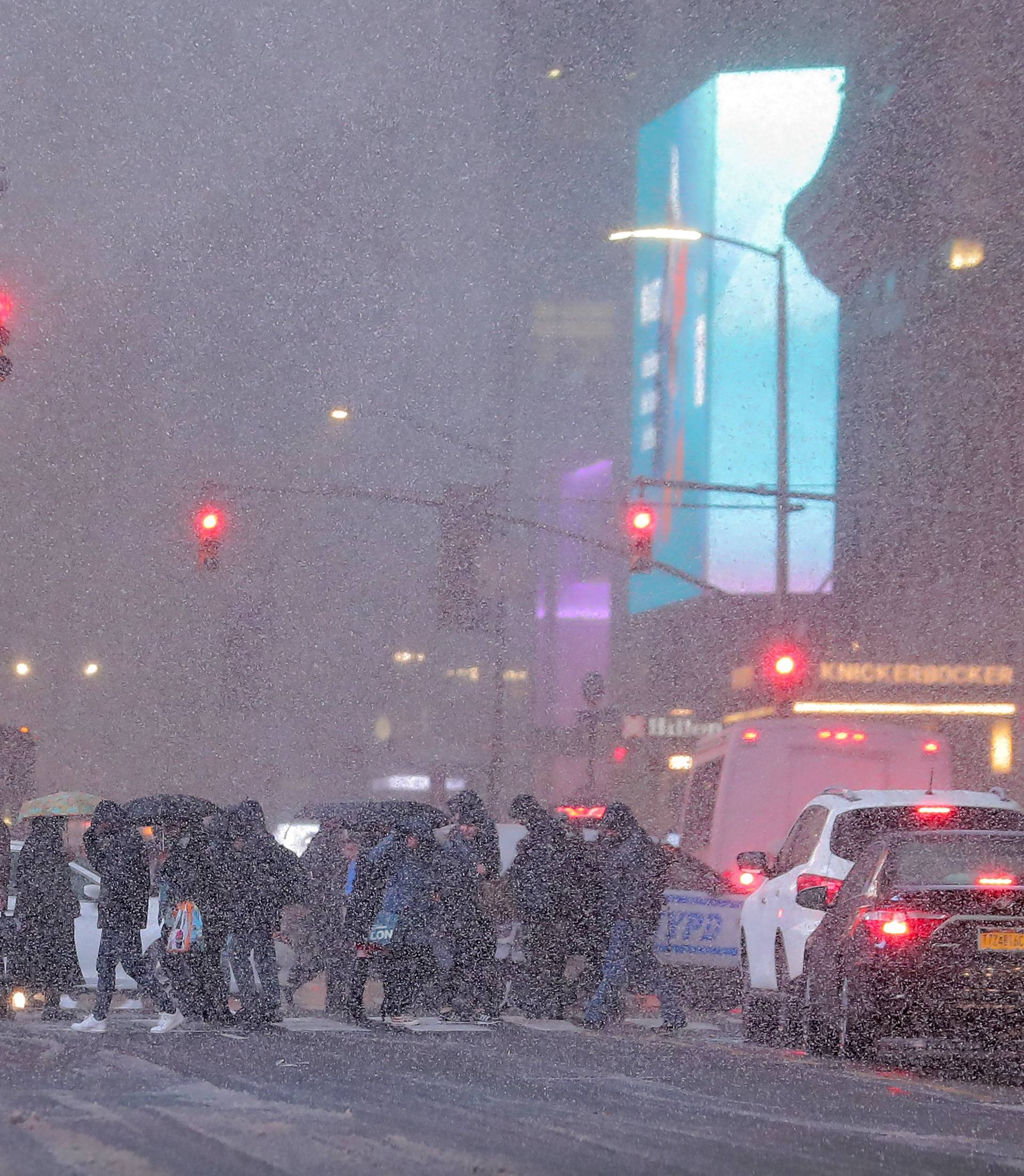 People walk through a snowstorm in Times Square during the evening commute in New York