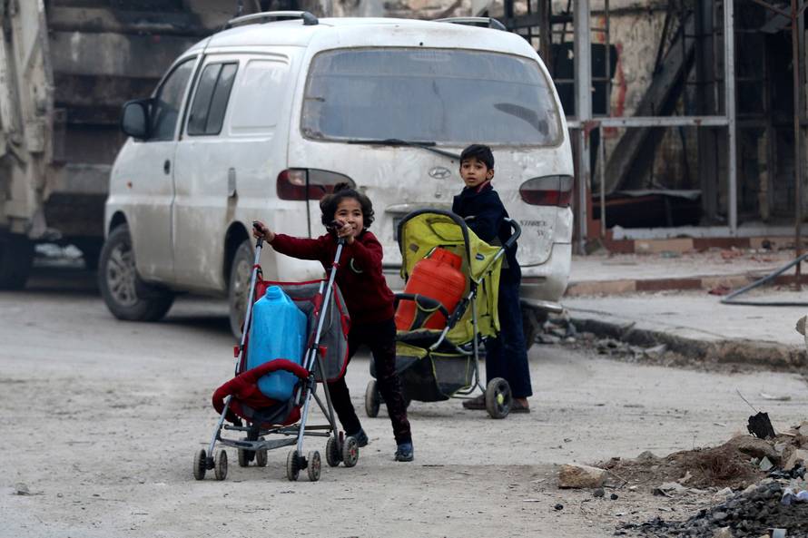 Children push containers in strollers as they flee deeper into the remaining rebel-held areas of Aleppo
