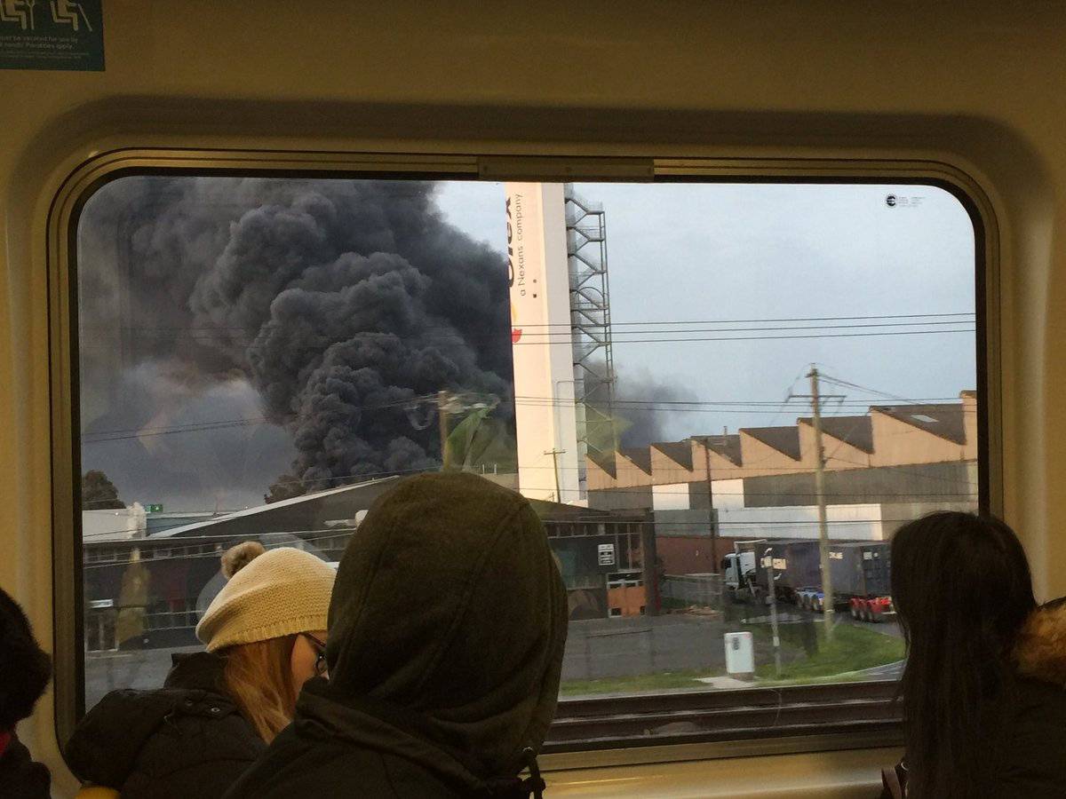Commuters on a train look at a thick plume of smoke in Melbourne