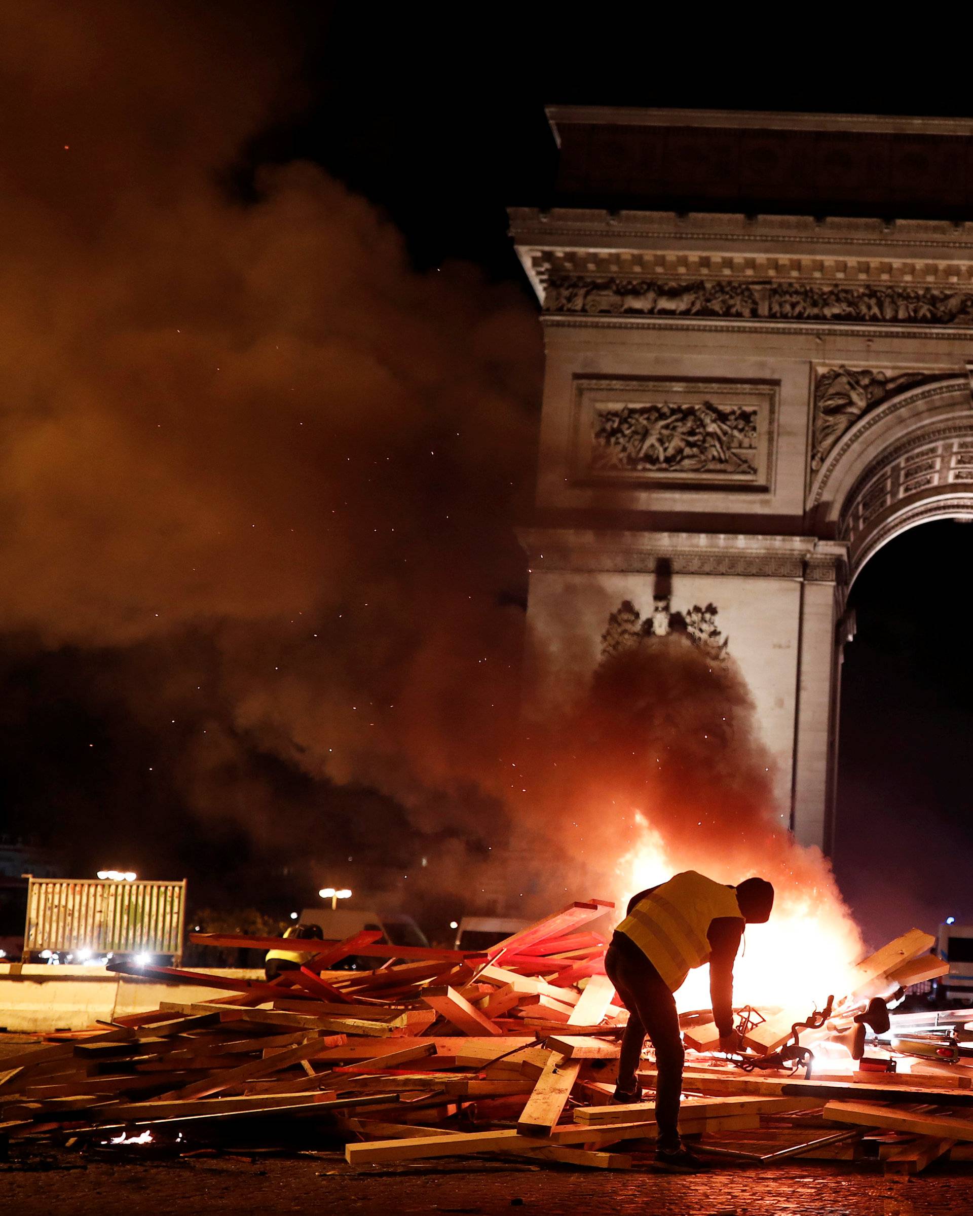 A protester is seen next to a burning barricade during a "Yellow vest"Â protestsÂ against higher fuel prices, on the Champs-Elysees in Paris
