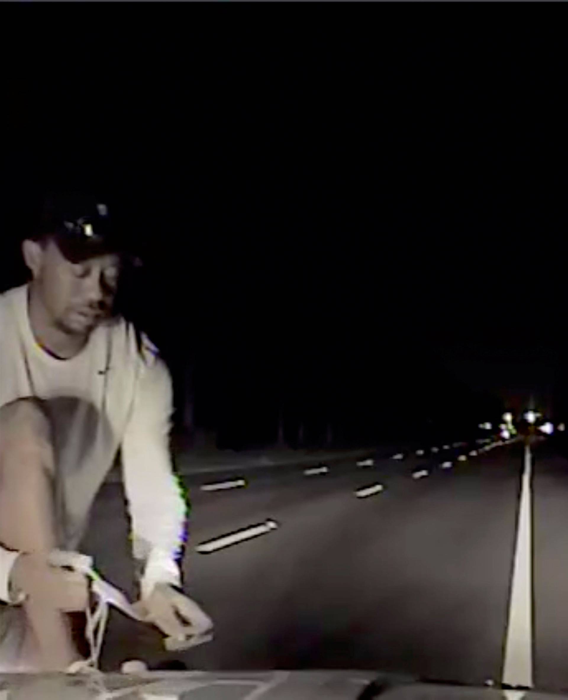 Tiger Woods is seen attempting to tie shoe laces before performing field sobriety tests in this still image from police dashcam video in Jupiter
