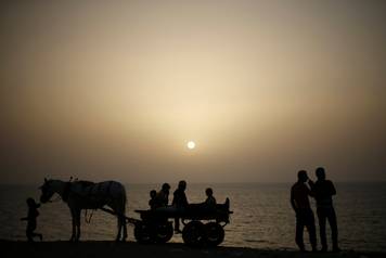 Palestinians ride a horse-drawn cart on a beach at Deir al-Balah refugee camp in the central Gaza Strip 