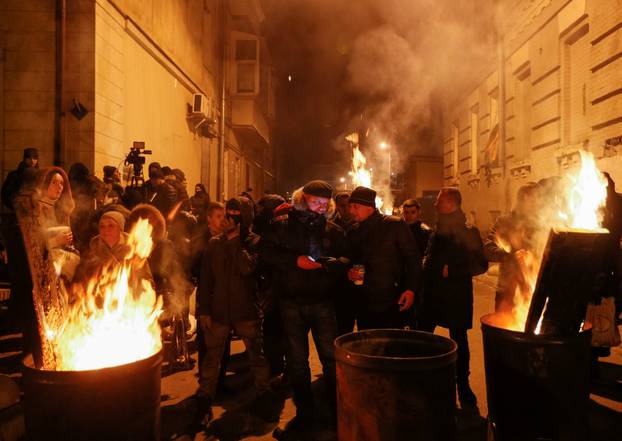 Supporters of former Georgian President Mikheil Saakashvili warm themselves at a bonfire near a temporary detention facility where Saakashvili was escorted after being detained in Kiev, Ukraine