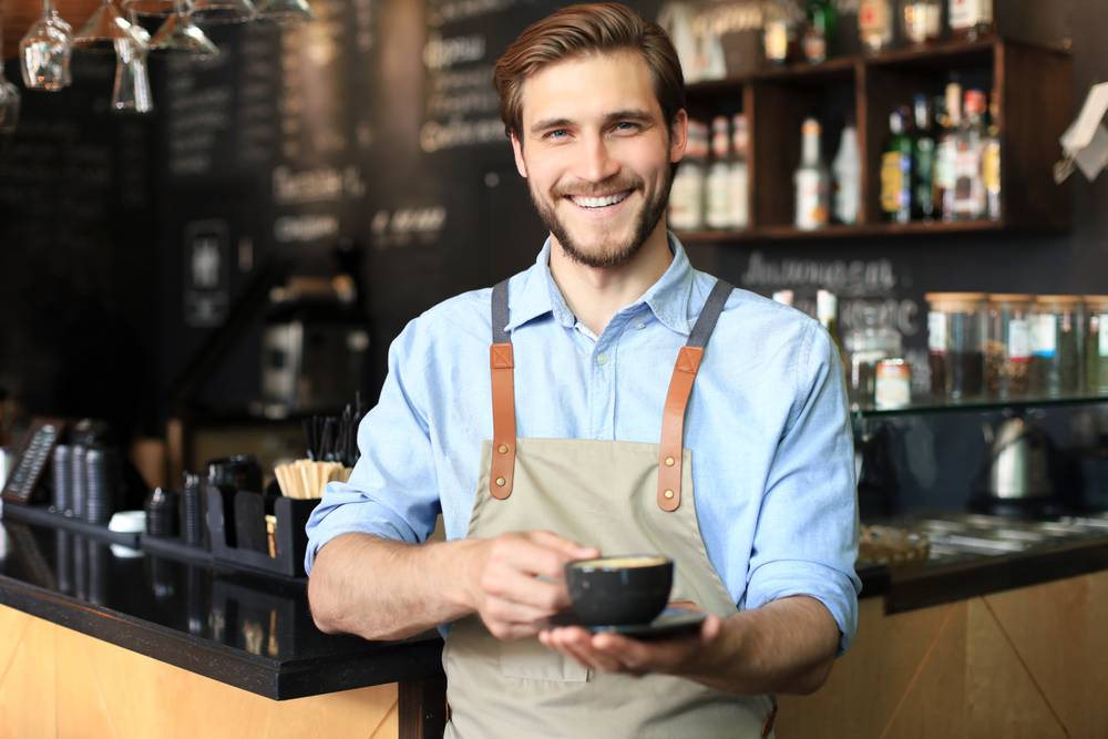 Handsome,Barista,Offering,A,Cup,Of,Coffee,To,Camera,At