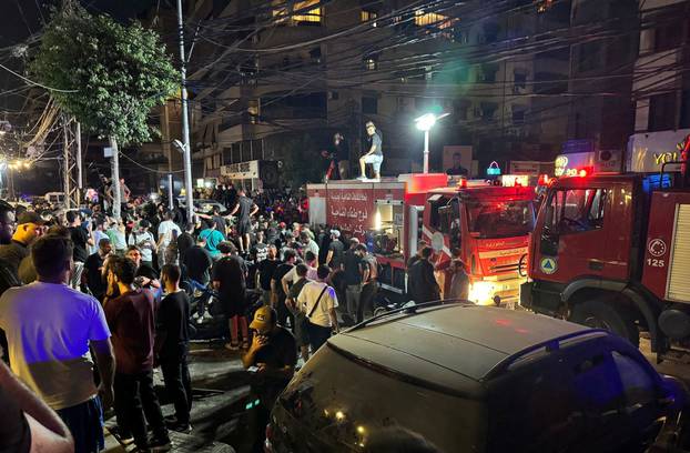 People gather near a site hit by what security sources said was a strike on Beirut's southern suburbs