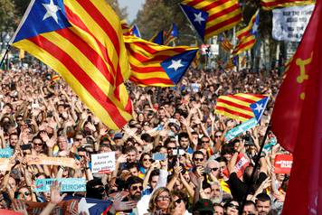 People react as they watch on giant screens a plenary session outside the Catalan regional parliament in Barcelona