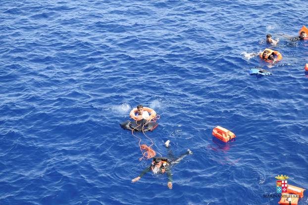 Migrants from a capsized boat are rescued during a rescue operation by Italian navy ships "Bettica" and "Bergamini" (unseen) off the coast of Libya