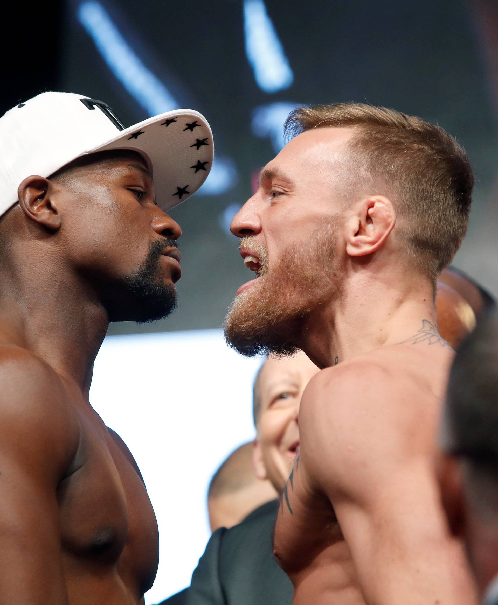 Undefeated boxer Floyd Mayweather Jr. (L) of the U.S. and UFC lightweight champion Conor McGregor of Ireland face off during their official weigh-in at T-Mobile Arena in Las Vegas