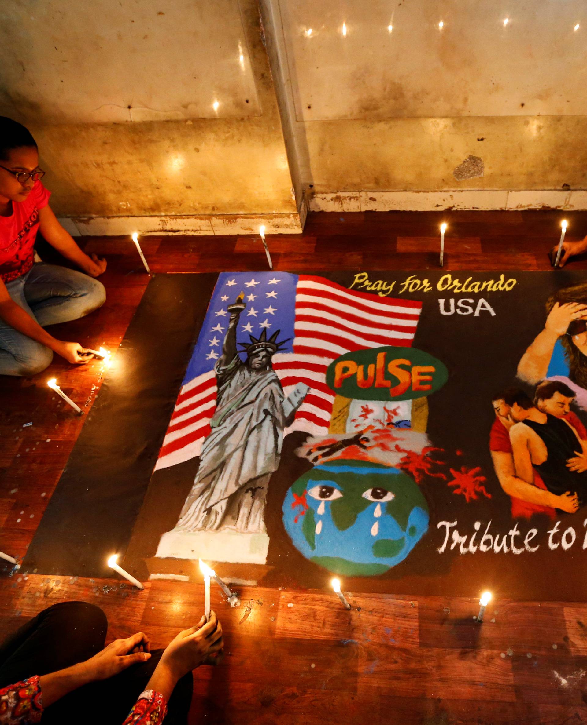 Students light candles around a rangoli, or mural made out of coloured powders, for the victims of the shooting at a gay nightclub in Orlando inside an art institute in Mumbai