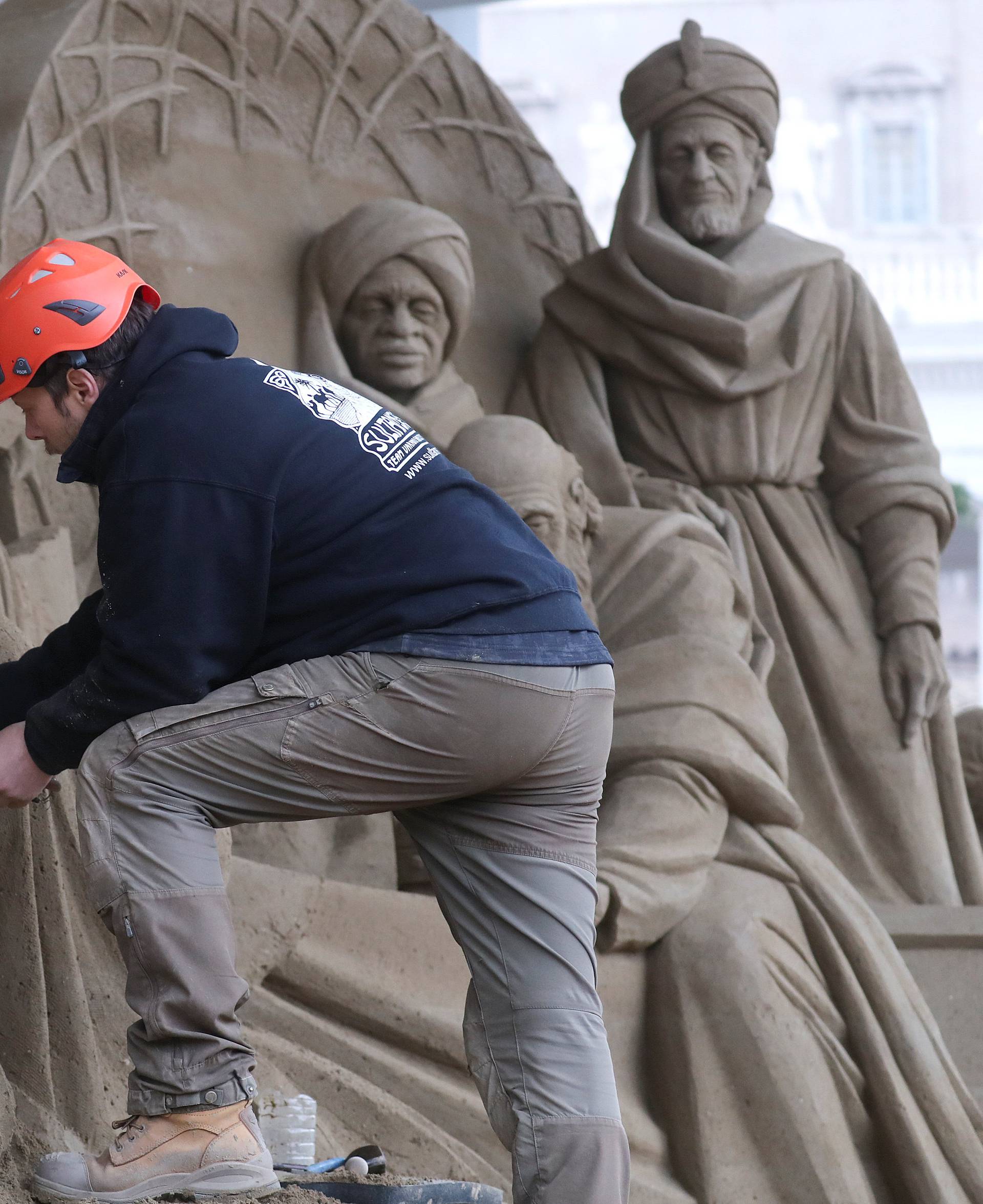 An artist works on a sand sculpture representing part of nativity scene in St. Peter's square at the Vatican