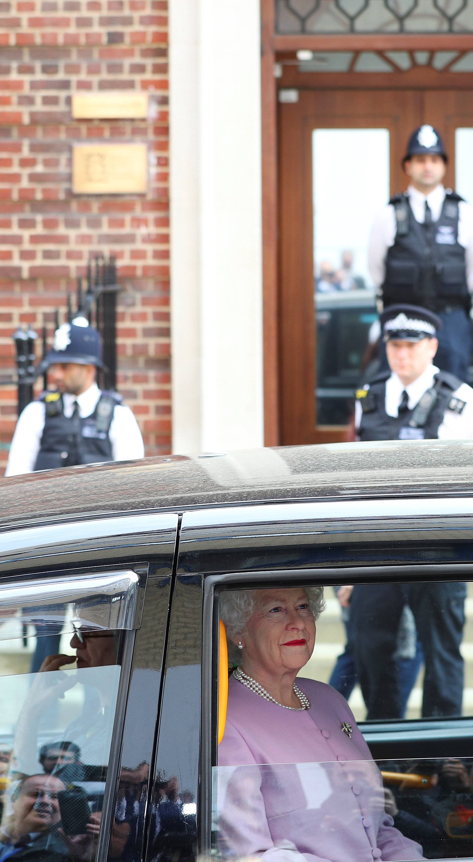 A person impersonating Britain's Queen Elizabeth is driven past the Lindo Wing of St Mary's Hospital after Britain's Catherine, the Duchess of Cambridge, gave birth to a son, in London
