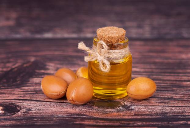 Argan oil on wooden background. Argan nuts and seeds, for cosmetic and beauty products. Natural argan fruit from Morocco.