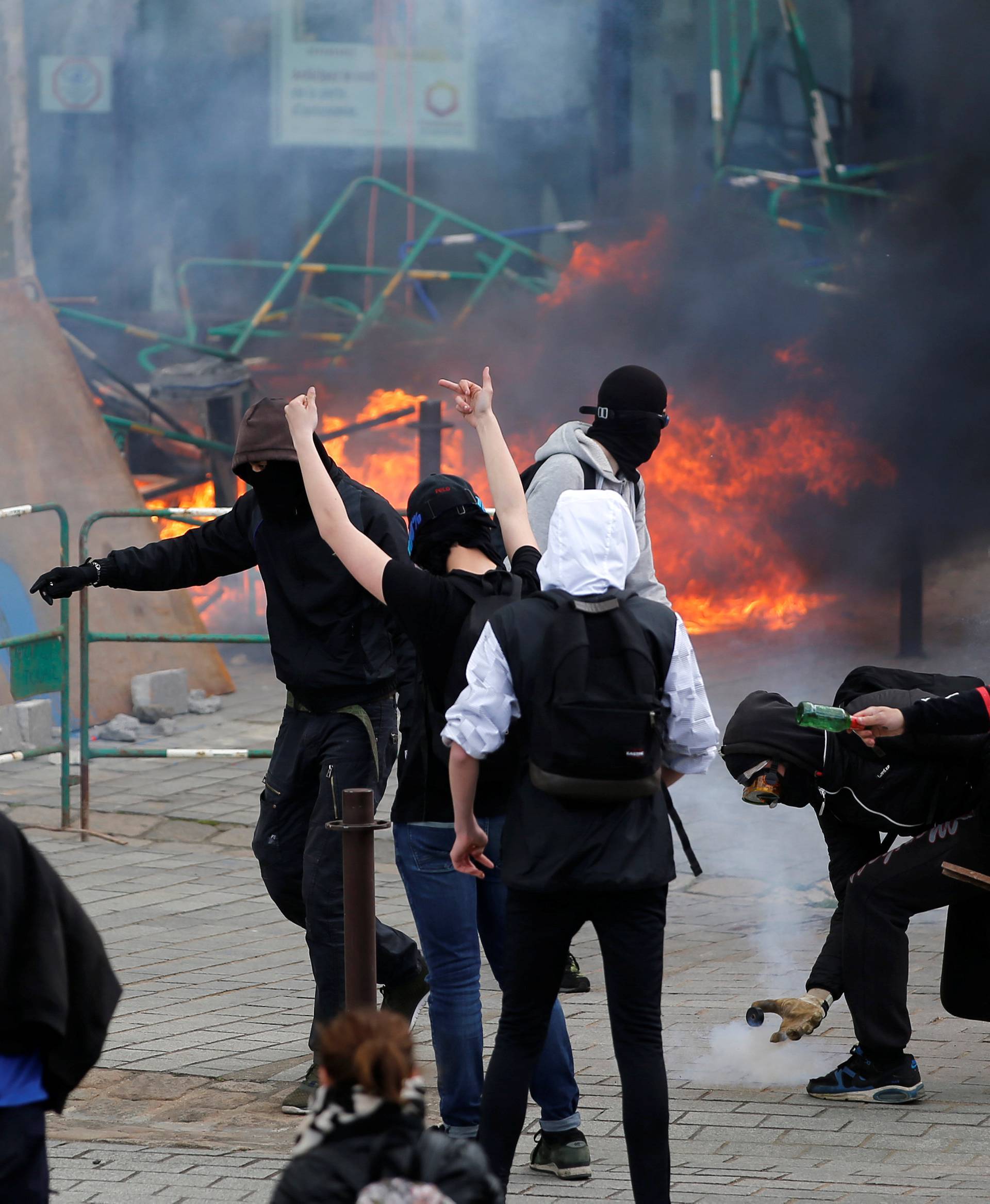 Youths take cover from tear gas during clashes during a demonstration against the French labour law proposal in Nantes