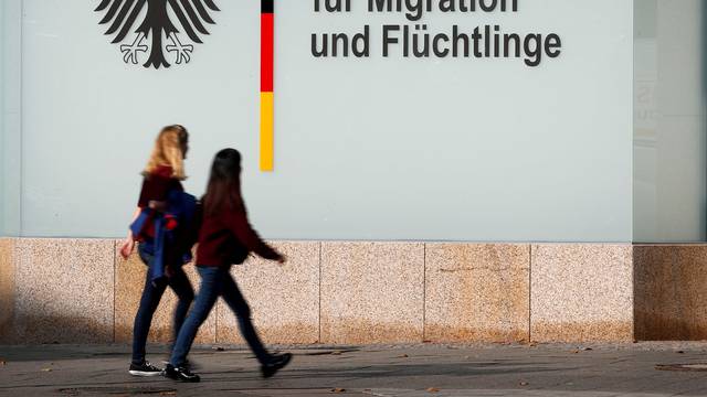 FILE PHOTO: People walk in front of an office building of the Federal Office for Migration and Refugees in Berlin