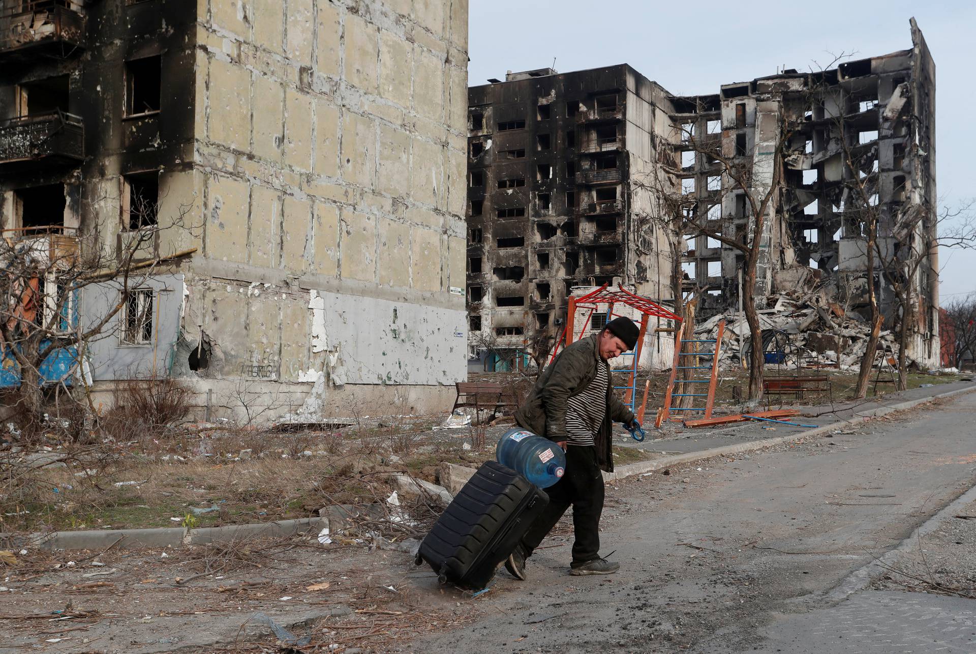 A local resident walks past destroyed apartment buildings in Mariupol