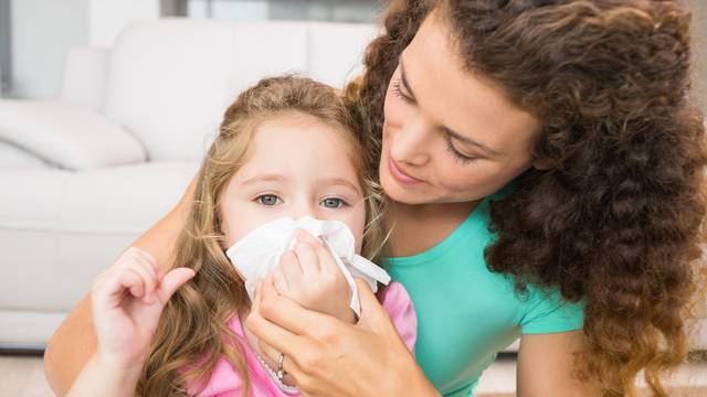 Mother helping her daughter blow her nose