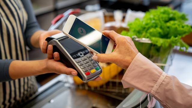 Unrecognizable female customer paying for groceries with smartphone