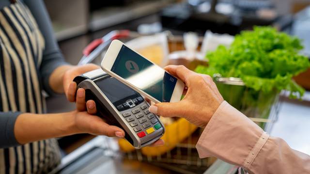 Unrecognizable female customer paying for groceries with smartphone