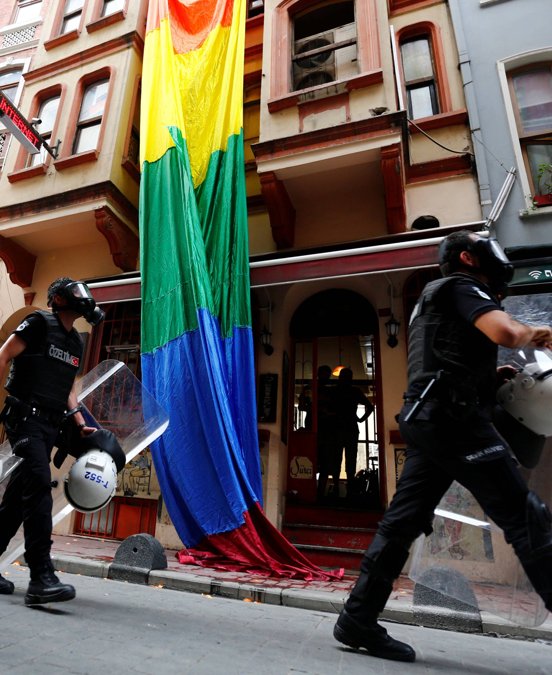 Riot police, with a rainbow flag in the background, chase LGBT rights activists as they try to gather for a pride parade, which was banned by the governorship, in Istanbul