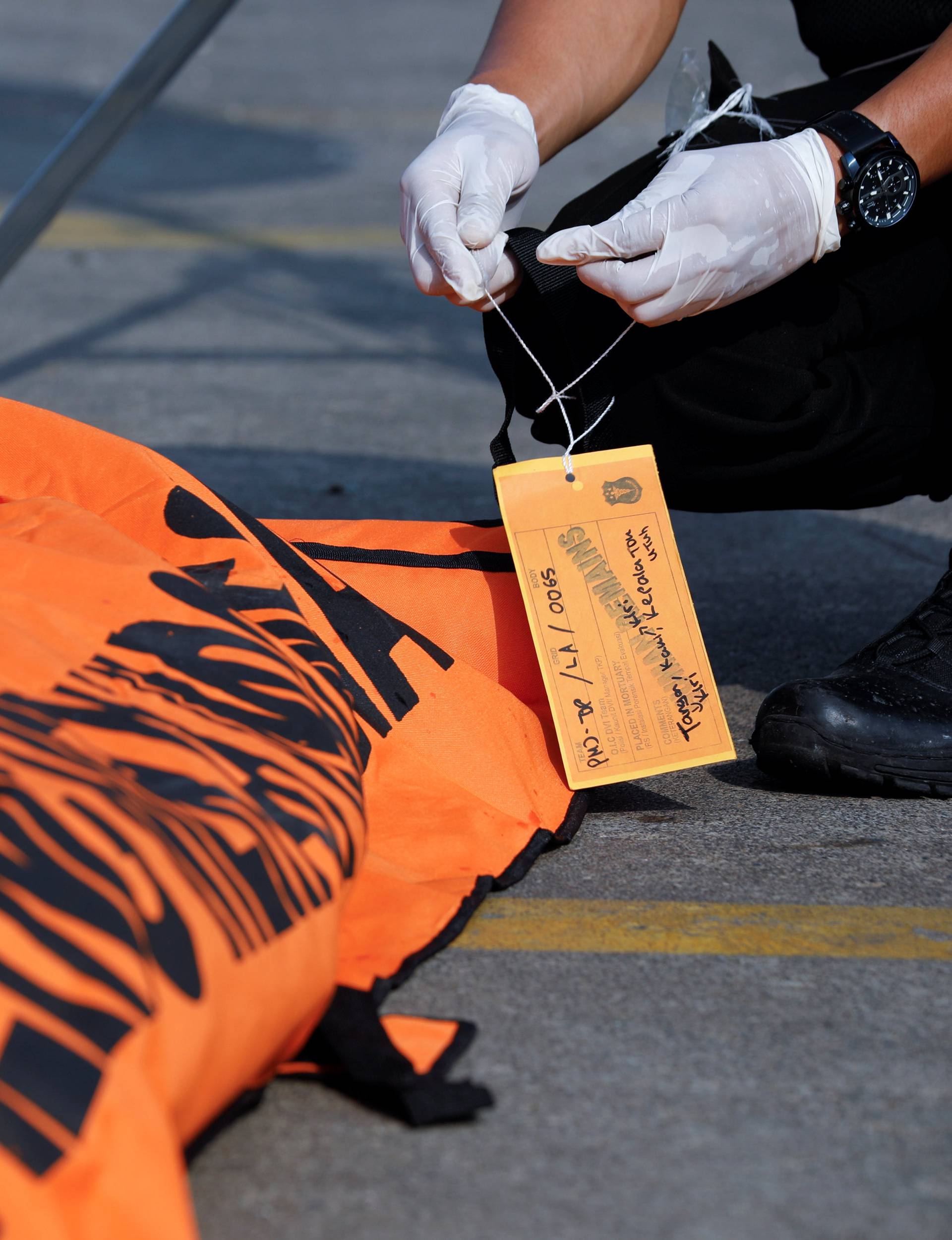 A rescue worker of the crashed Lion Air flight JT610 labels a body bag at the Tanjung Priok port in Jakarta