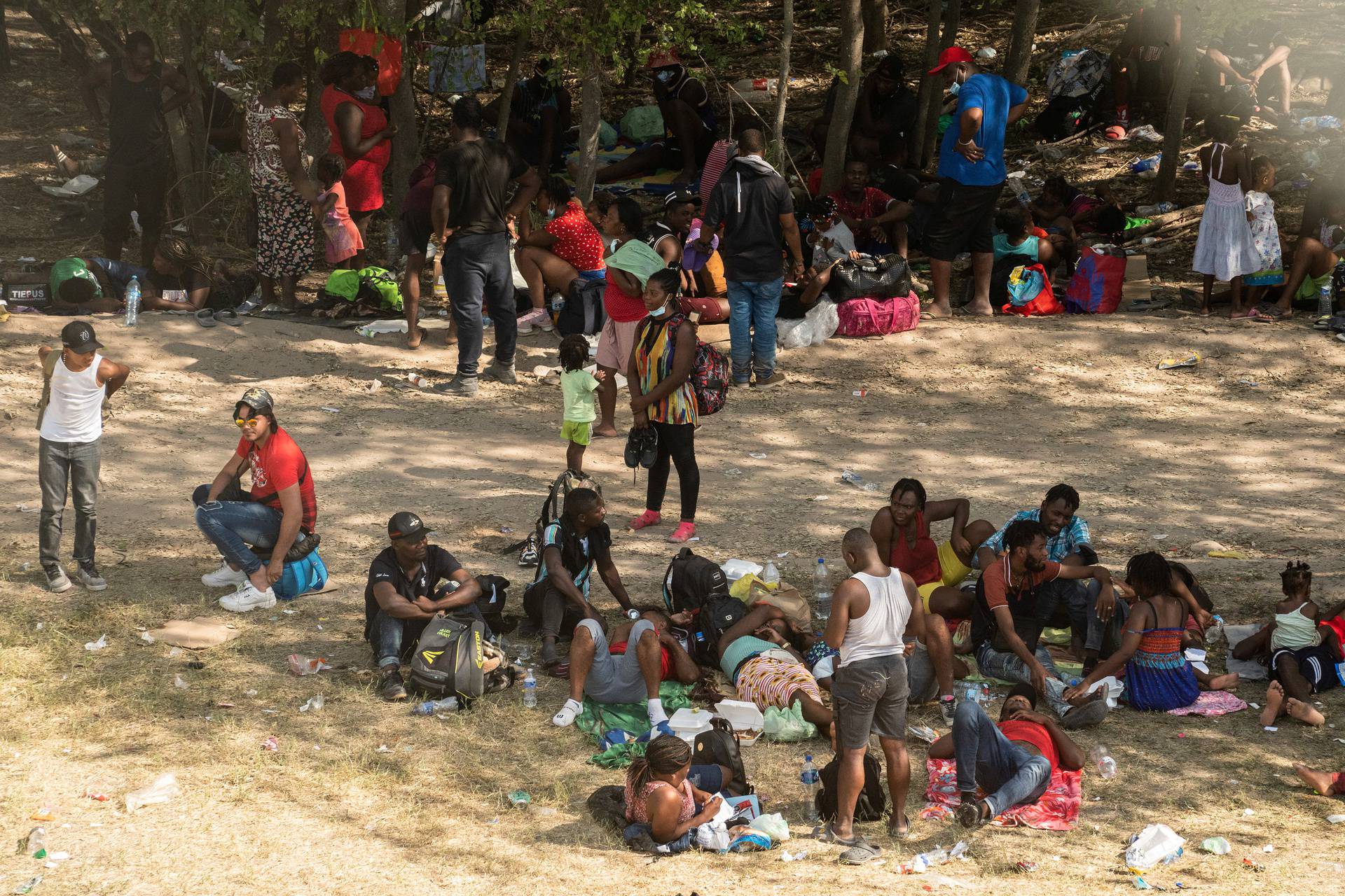 Asylum-seeking migrants wait to be processed under the international bridge in Del Rio, TX