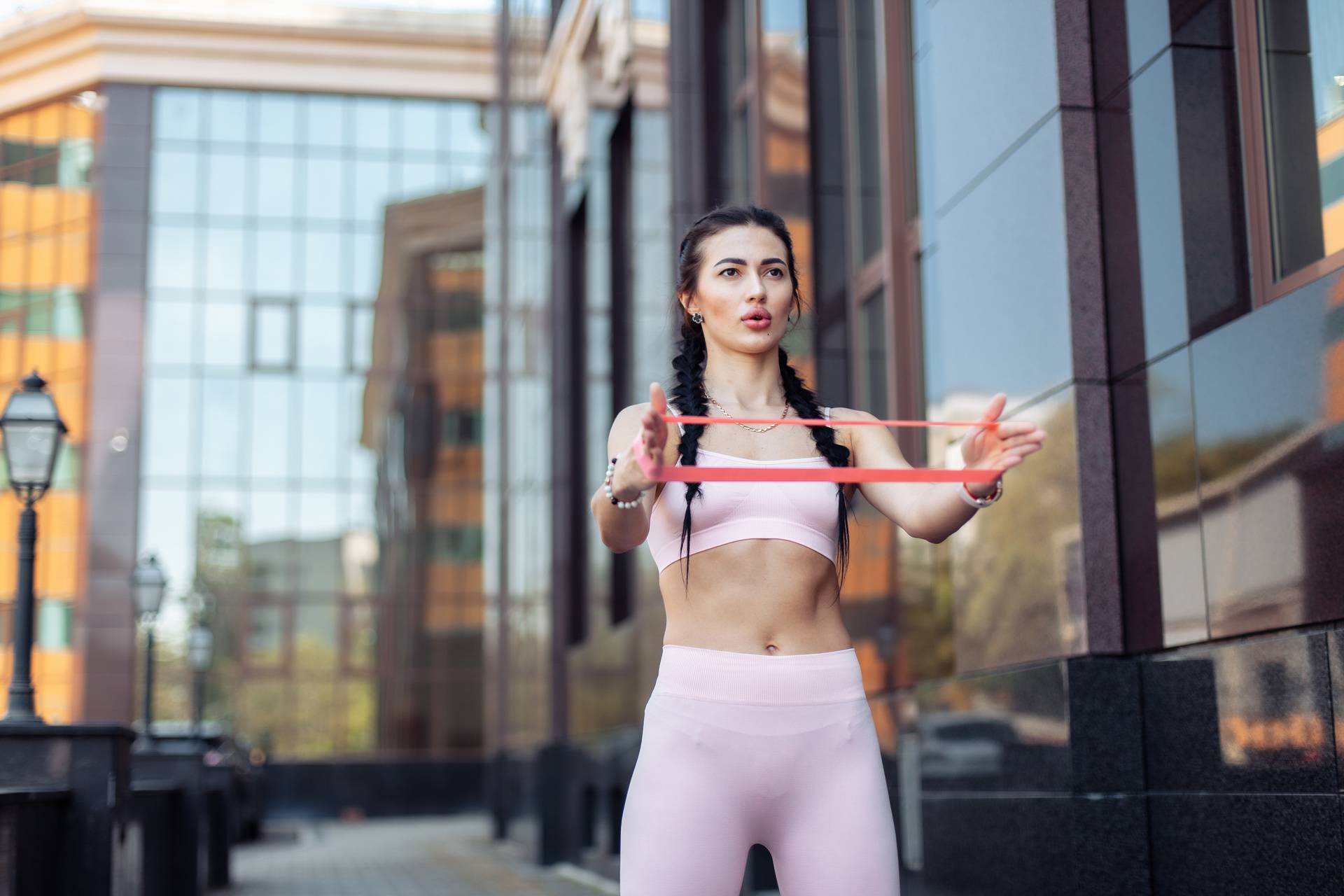 Athletic woman doing exercise with a resistance rubber band during her street workout