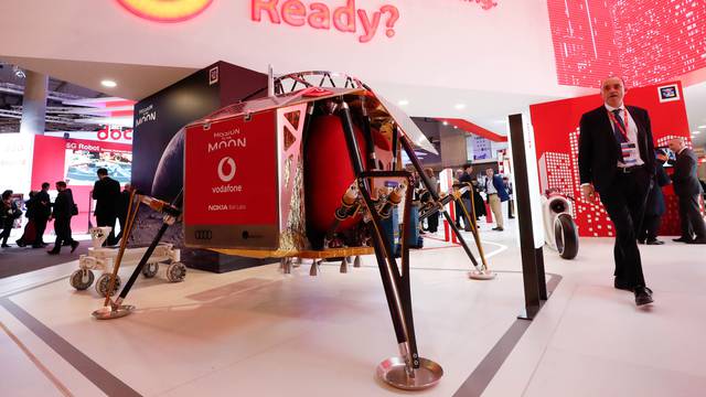 A visitor walks past a mobile mast with an Audi lunar exploration vehicle during the Mobile World Congress in Barcelona