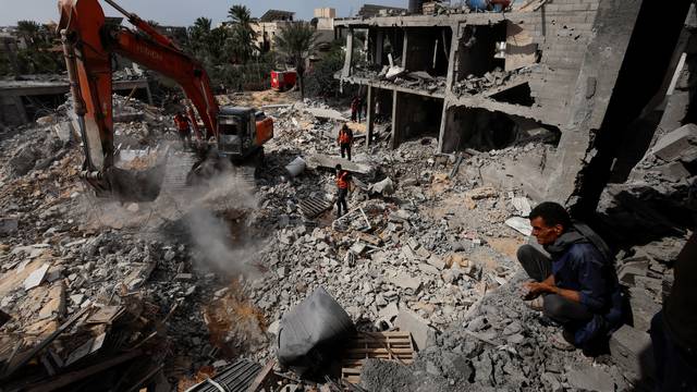 Palestinians search for casualties under the rubble of a house destroyed by Israeli strikes in Khan Younis