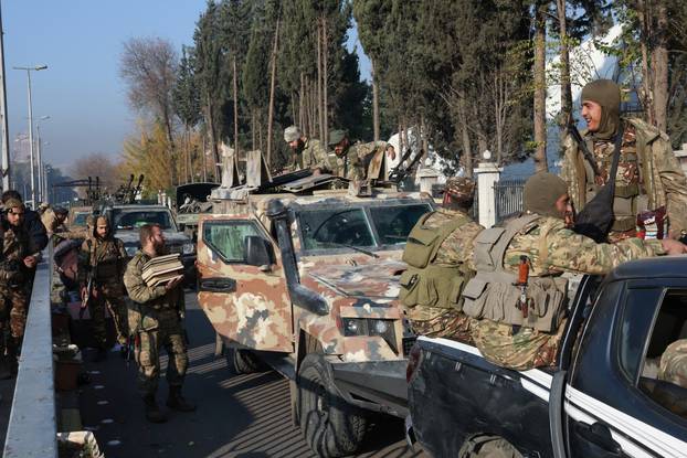 Rebel fighters sit on vehicles, in Damascus