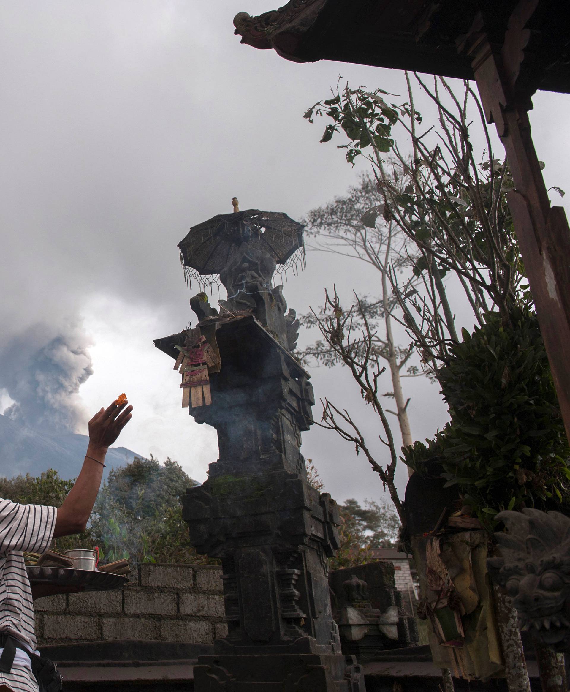 A villager prays at his house as Mount Agung eruption at Besakih village in Karangasem