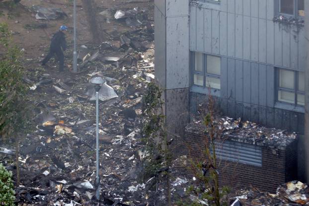 A firefighter walks around the base of the tower block that was destroyed in a fire disaster, in north Kensington, West London