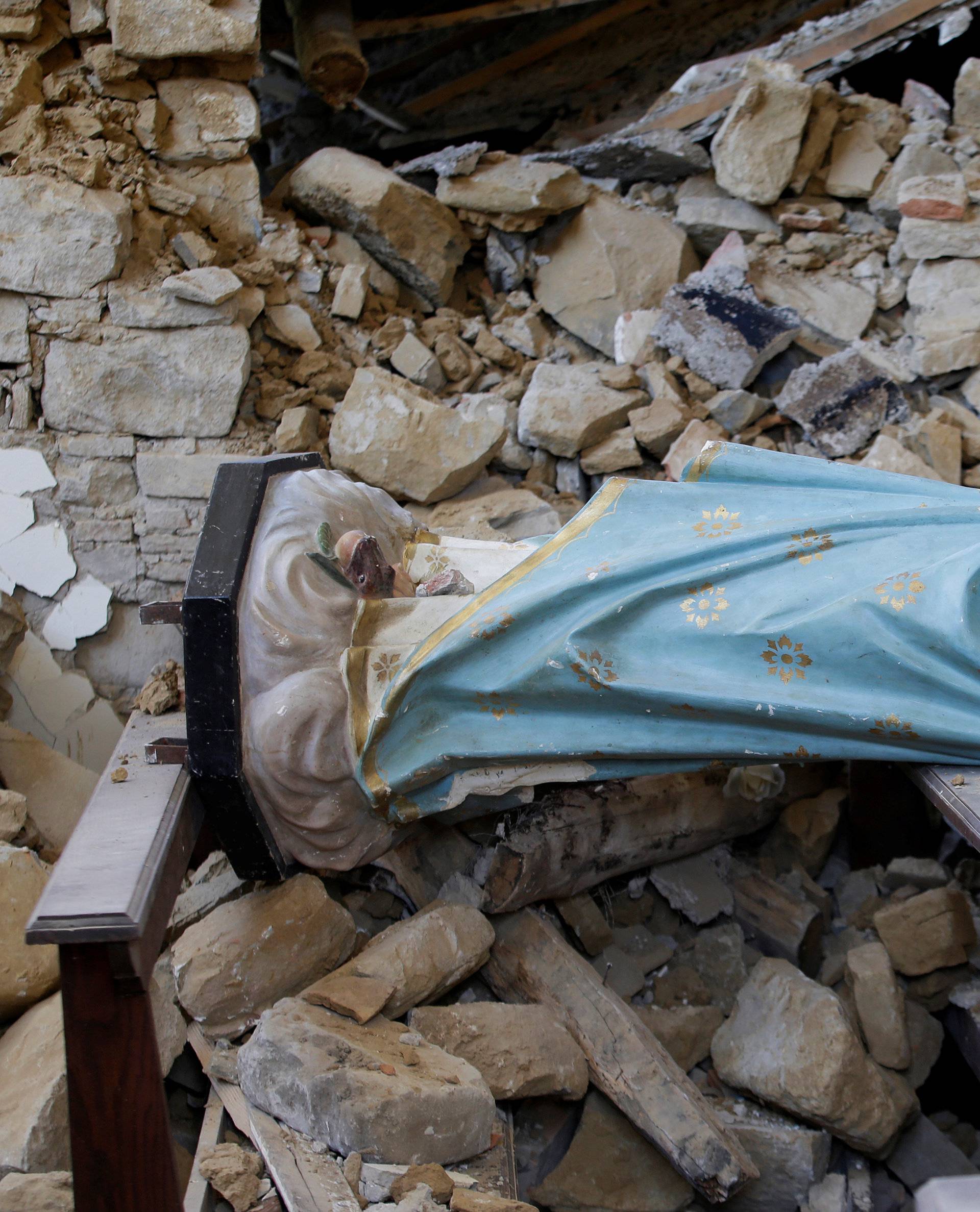 A damaged Virgin Mary statue is seen in a church following an earthquake at Cossito near Amatrice