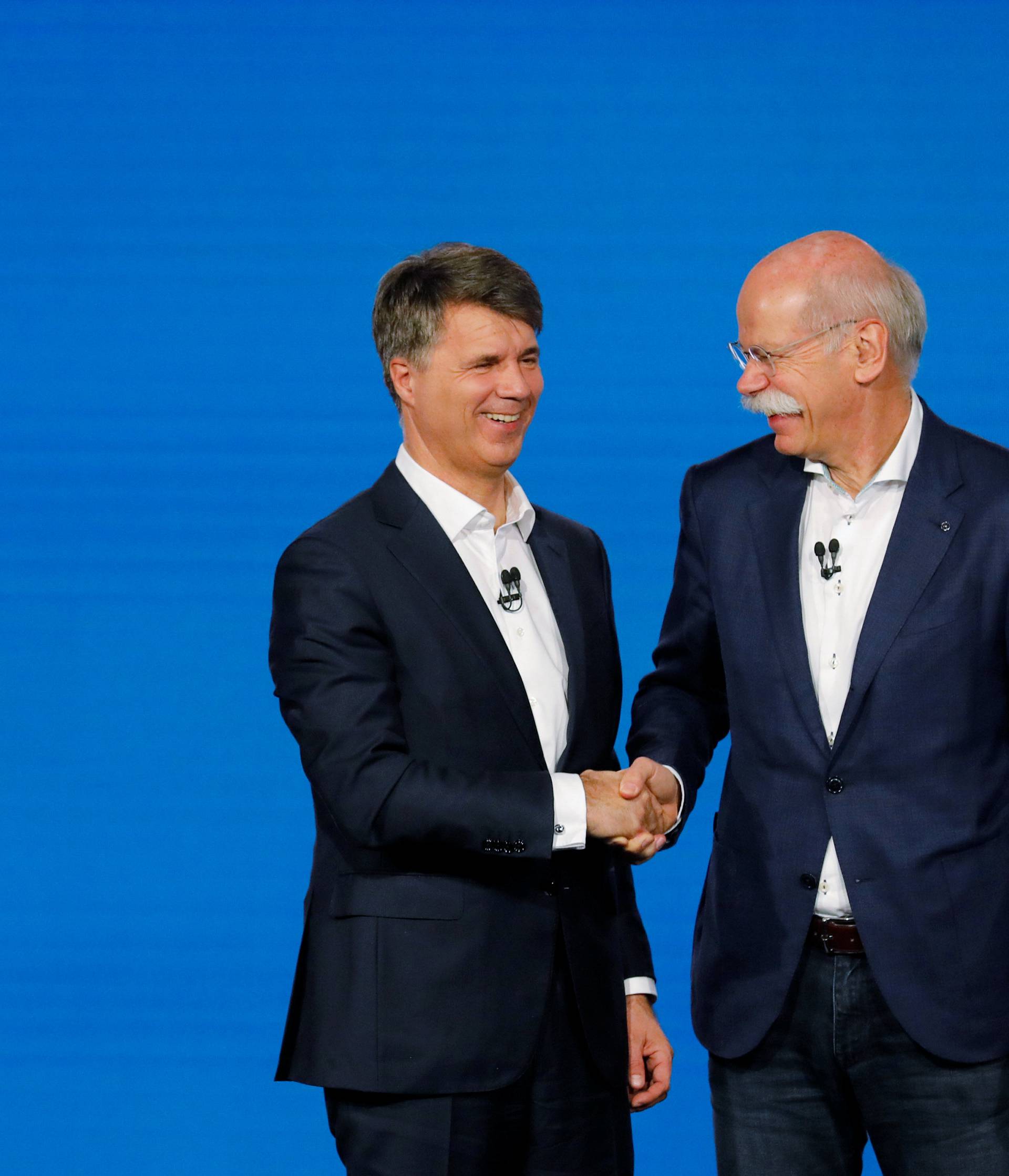 Harald Kruger, CEO and Chairman of the Board of Management of BMW AG and Dieter Zetsche, CEO of Daimler AG, shake hands at a news conference to present plans for combining the companies' car-sharing businesses, in Berlin
