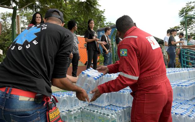 Volunteers pass bottles of water for people affected by a failed iron ore tailings dam owned by Brazilian miner Vale SA that burst, in Brumadinho