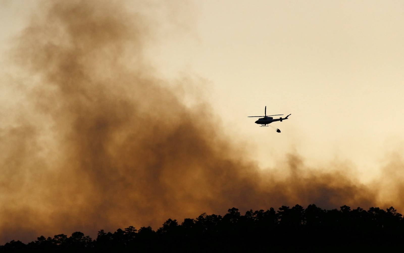 A firefighting helicopter flies over a forest fire in Arico, on the Canary island of Tenerife
