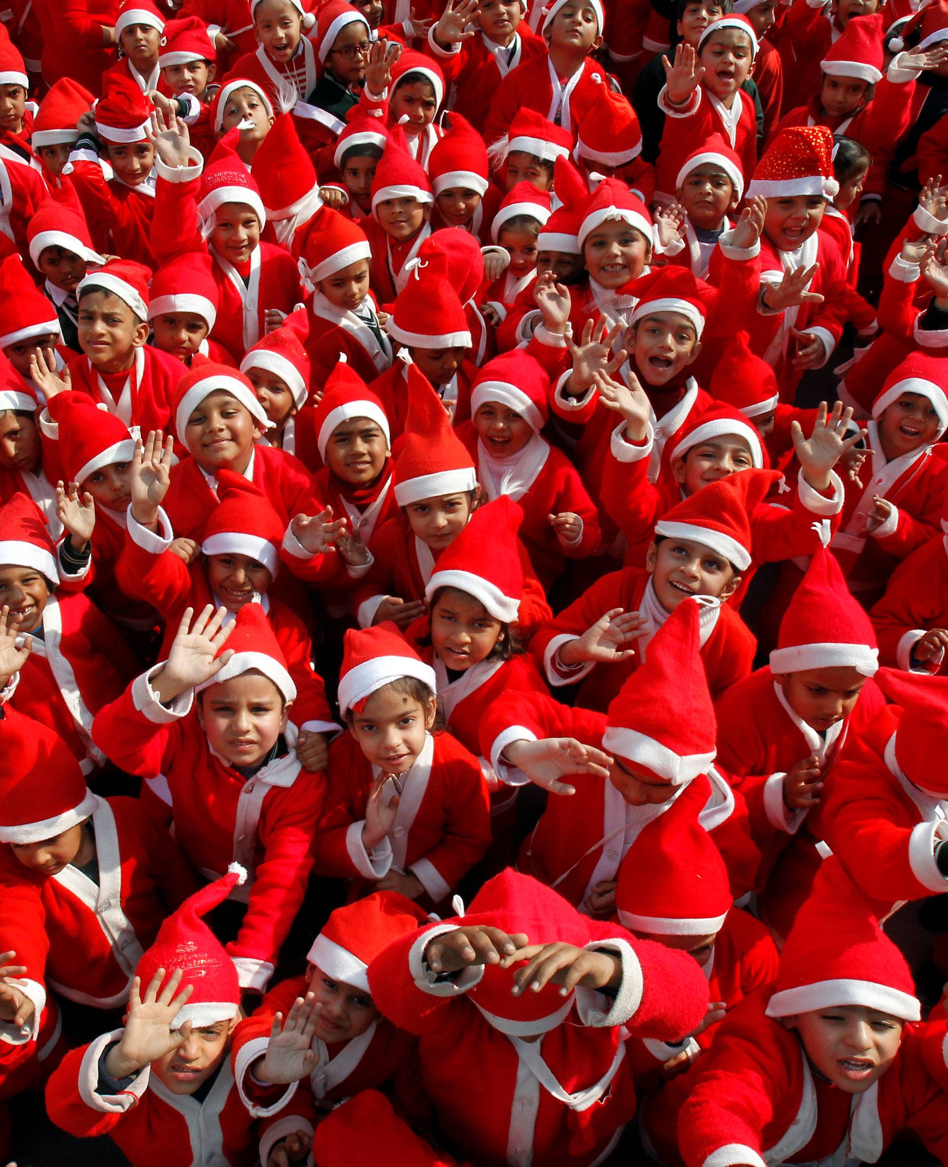 Children dressed in Santa Claus costumes wave as they participate in Christmas celebrations at a school in Chandigarh