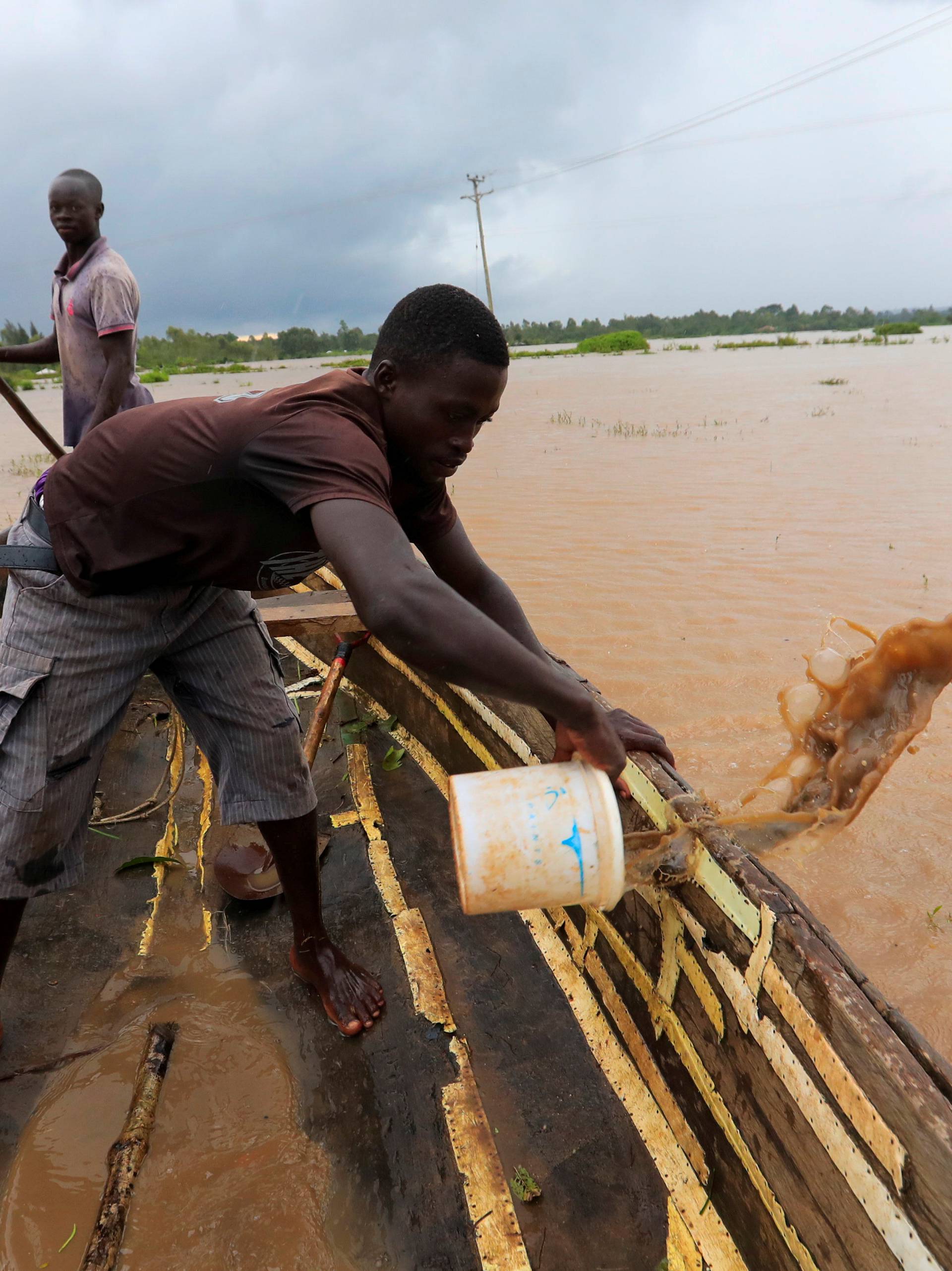 A man removes flood water from a boat as residents evacuate from their homes after River Nzoia burst its banks and due to the backflow from Lake Victoria, in Buyuku village of Budalangi