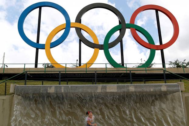 FILE PHOTO: A child plays in water near Olympic rings placed at Madureira Park ahead of the Rio 2016 Olympic Games in Rio de Janeiro