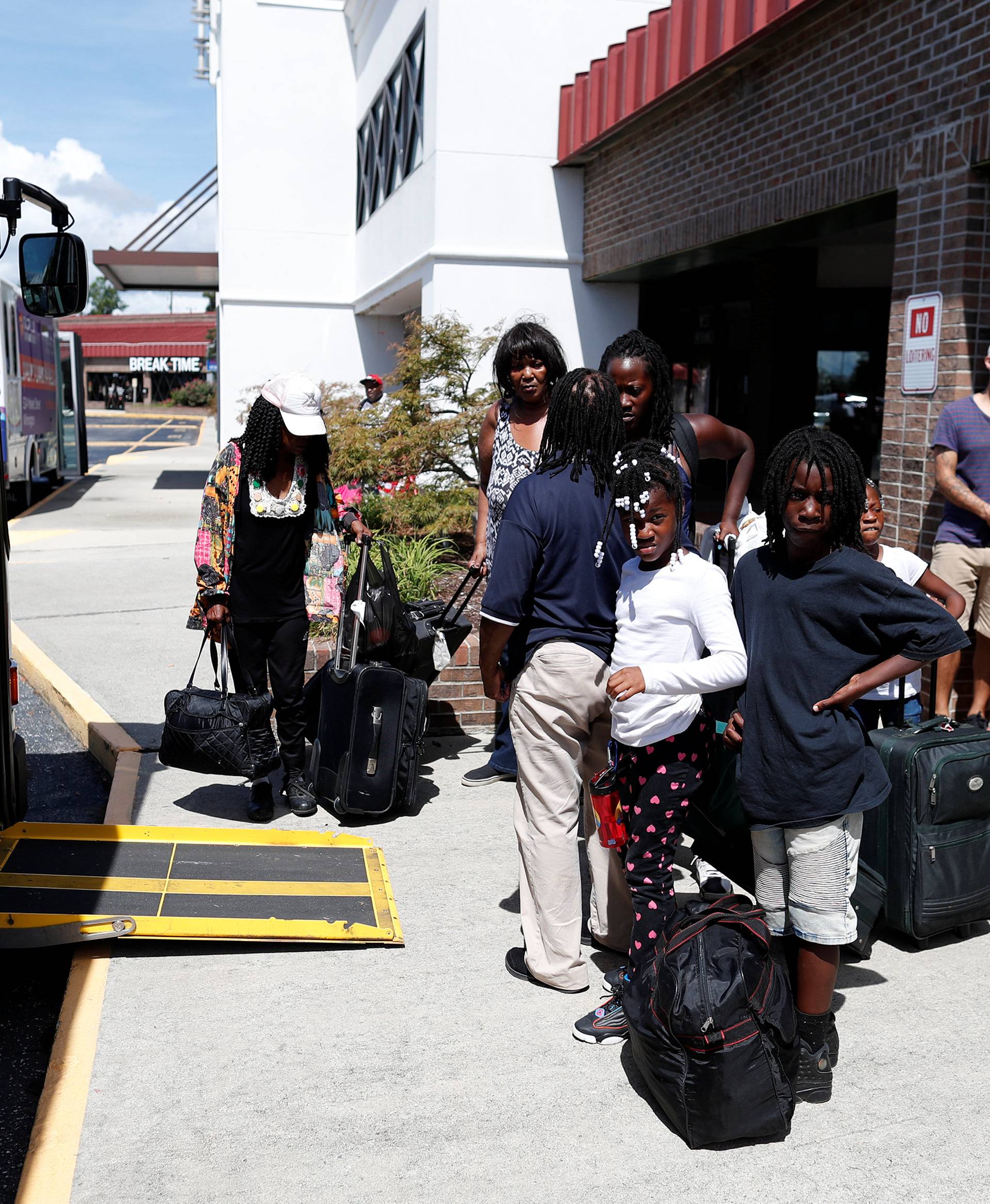 People wait in line for an evacuation bus to Raleigh, North Carolina ahead of the arrival of Hurricane Florence in Wilmington